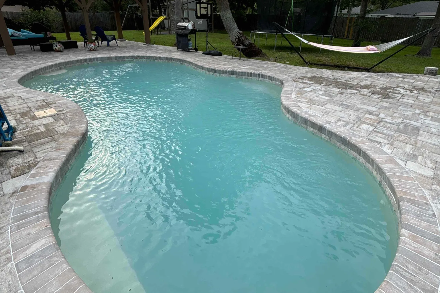 Freeform paver pool deck installation with tumbled stone coping by Jax Pavers in Jacksonville FL
