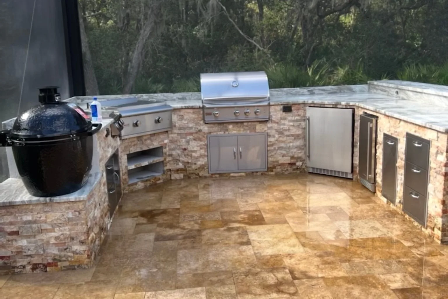 L-shaped outdoor kitchen with kamado smoker, built-in grill, and natural stone veneer by Jax Pavers in Jacksonville FL