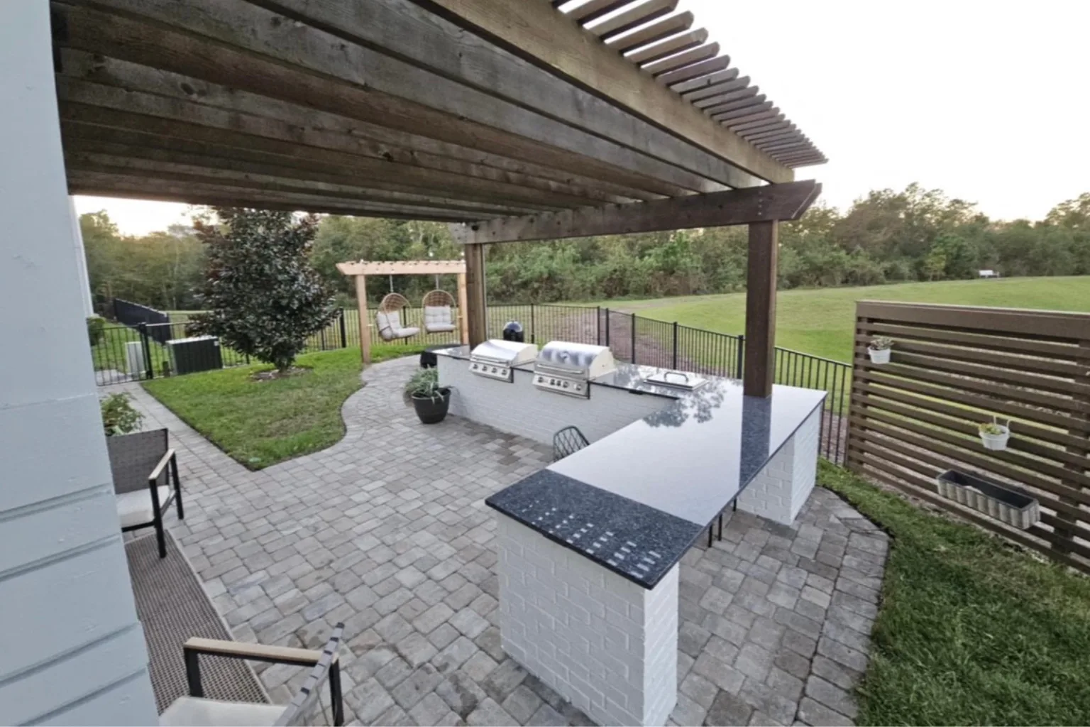 Pergola and outdoor kitchen installation with paver patio and horizontal privacy fence by Jax Pavers in Jacksonville FL